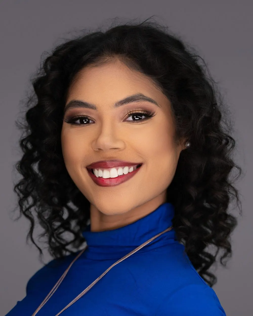 Smiling woman in a blue top against a dark studio background